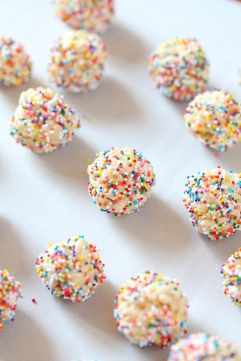 sprinkle covered donuts sitting on top of a white table next to each other