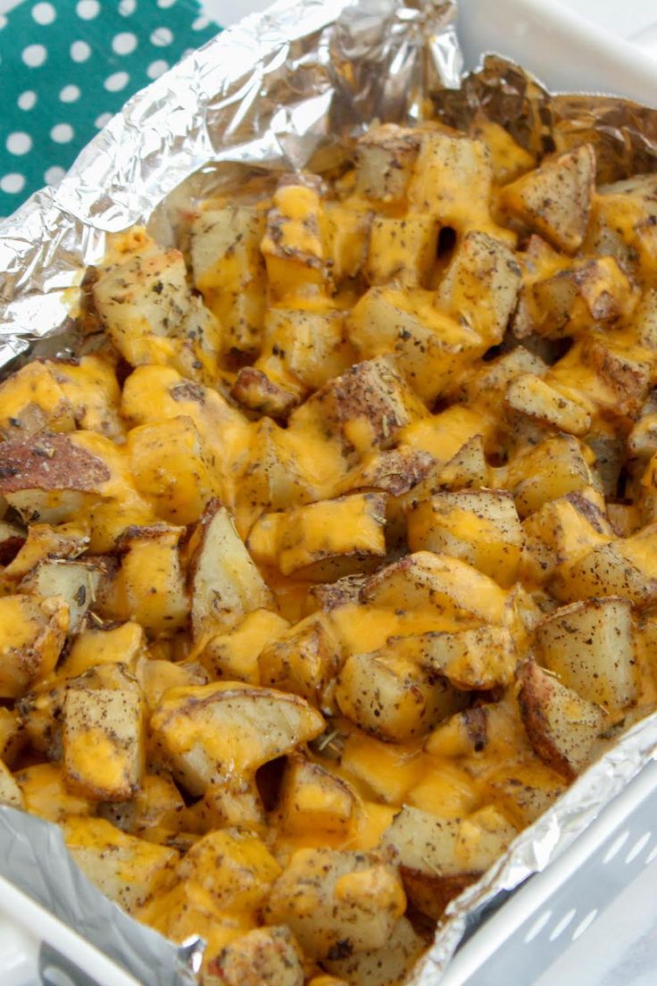 a casserole dish with potatoes and cheese in foil on a blue polka dot tablecloth