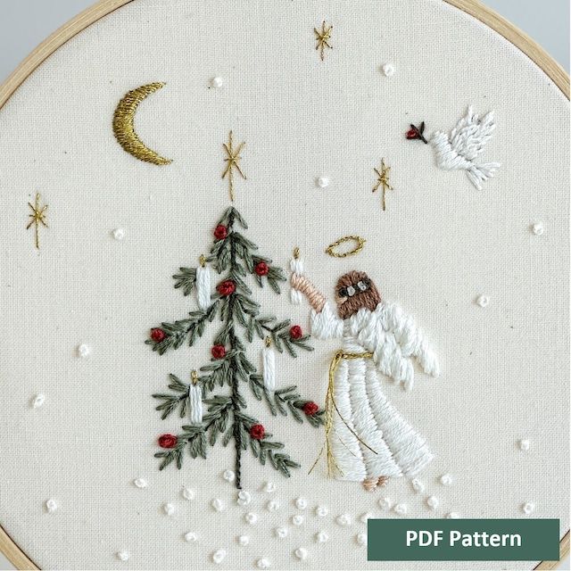 an embroidered christmas tree with angel and doves in the snow, surrounded by stars