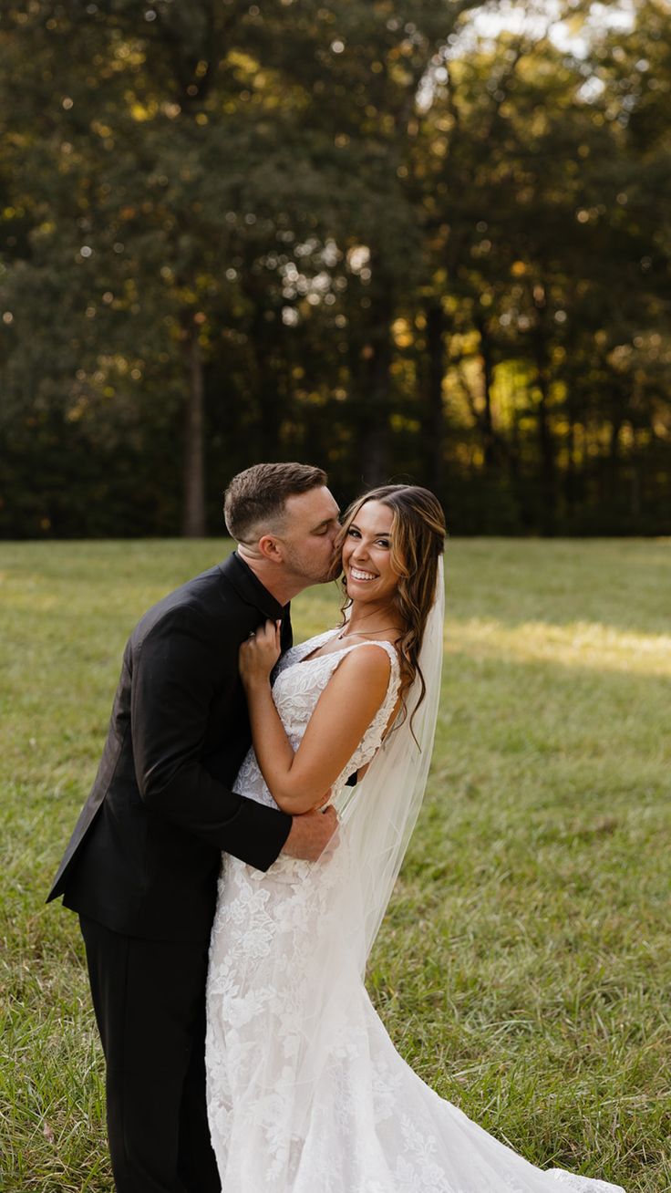 a bride and groom kissing in the grass