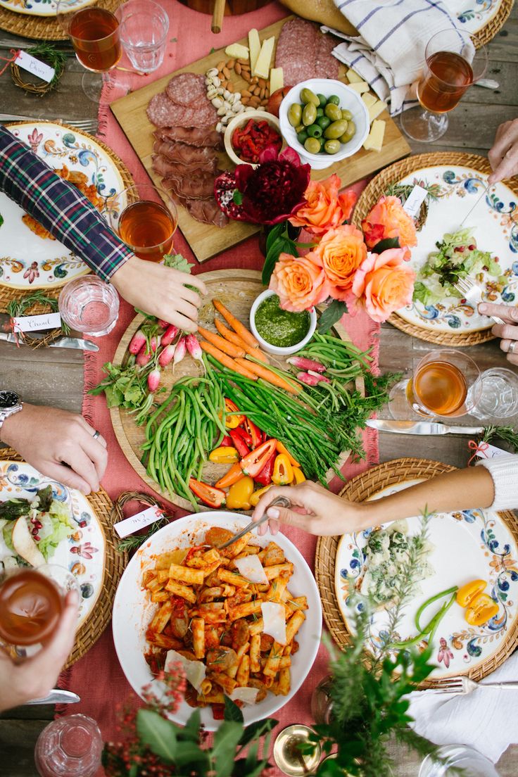 people sitting at a table with plates and bowls of food in front of each other