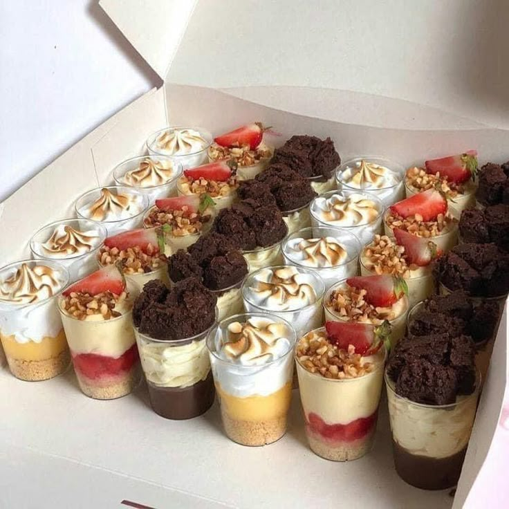 there are many desserts in the box on the table with strawberries and nuts