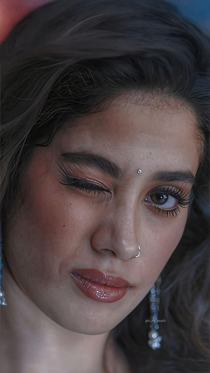 a close up of a woman with earrings on her head and nose piercings around her eyes