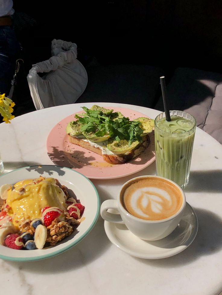 a table topped with two plates of food and cups of coffee next to each other