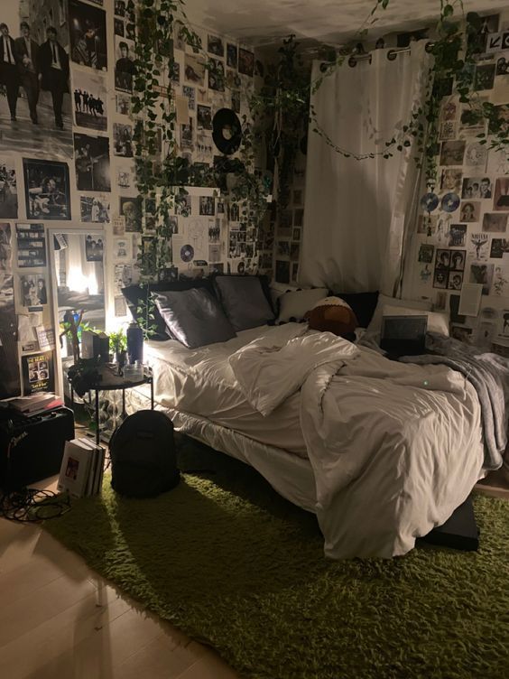 an unmade bed sitting on top of a green rug in a room filled with pictures