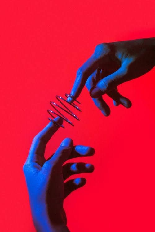 two hands reaching out towards each other over a red and blue background with one hand holding a comb