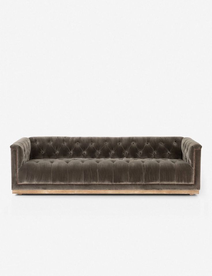 a grey velvet couch with wooden legs