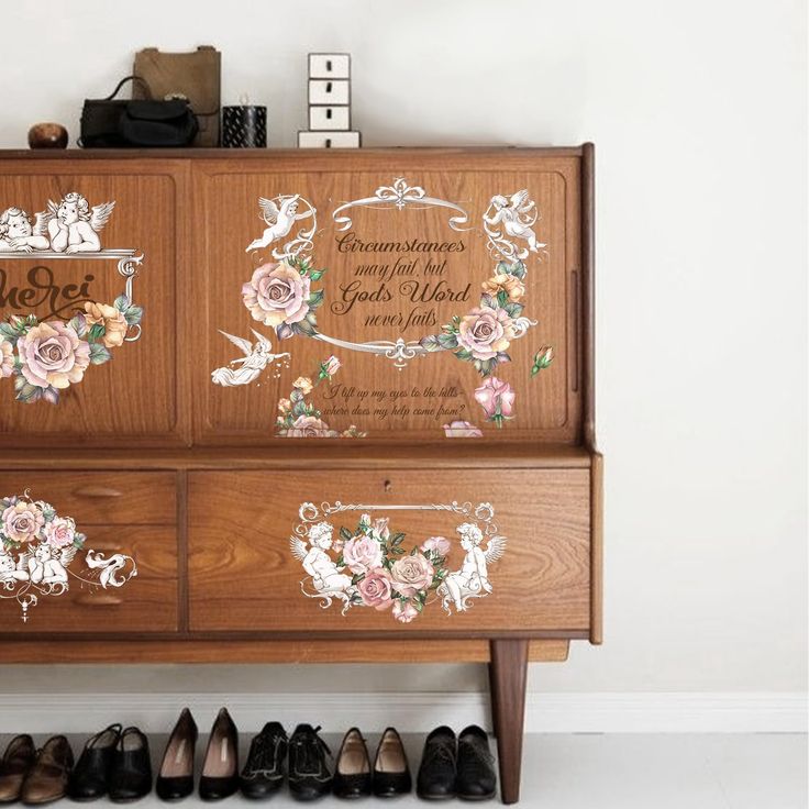 a wooden cabinet with floral decals on the doors and drawers, along with several pairs of shoes