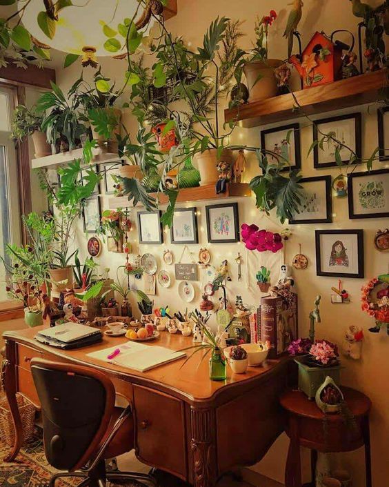 a desk with lots of plants and pictures on the wall