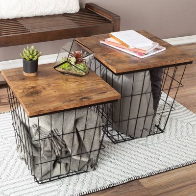 two tables with wire baskets on them sitting on a rug in front of a couch