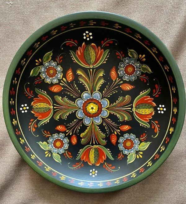 a decorative bowl with flowers painted on the outside and inside, sitting on a cloth covered surface