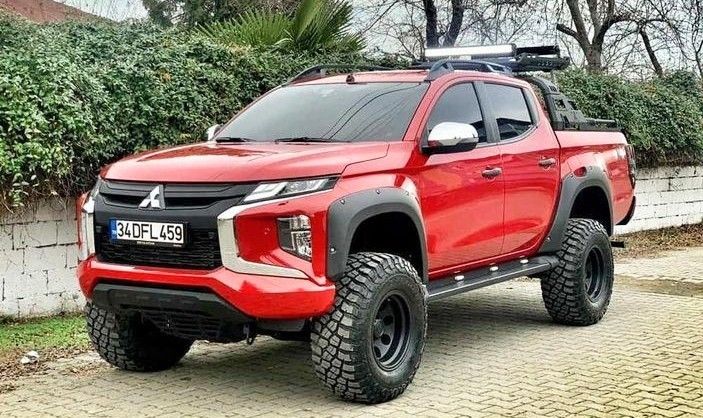 a red pick up truck parked in front of a hedged area with trees and bushes