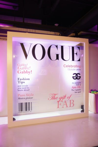 the front cover of a magazine on display at a fashion show with purple lighting in the background