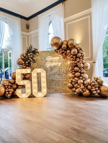 a 50th birthday party with balloons and lights on the dance floor in front of a large number 50 sign