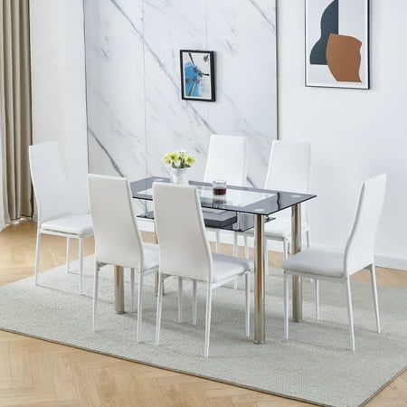 a dining room table with white chairs and a rug on the floor in front of it