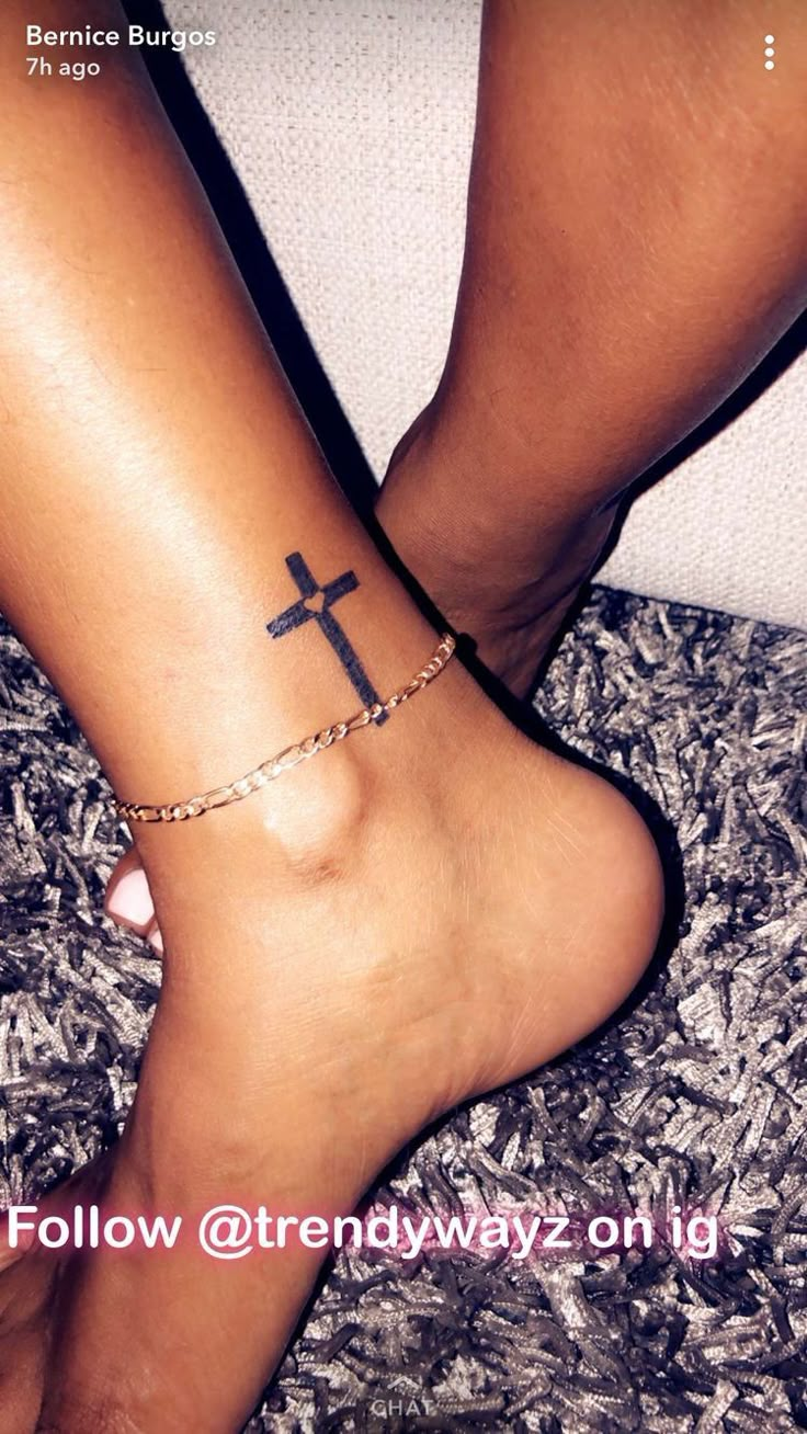 a woman's foot with a cross tattoo on it