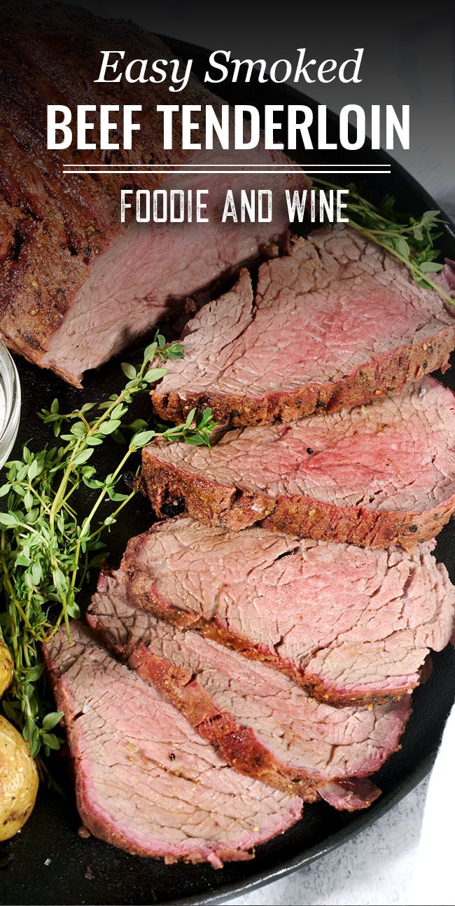 sliced beef tenderloin on a black plate with potatoes and parsley next to it