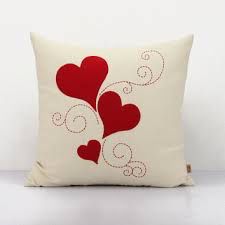 a white pillow with red hearts on the front and back, against a white background