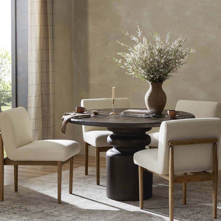 a dining room table with chairs around it and a vase filled with flowers on top