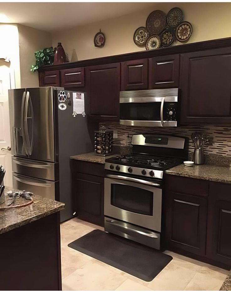 a kitchen with stainless steel appliances and granite counter tops, along with dark wood cabinets