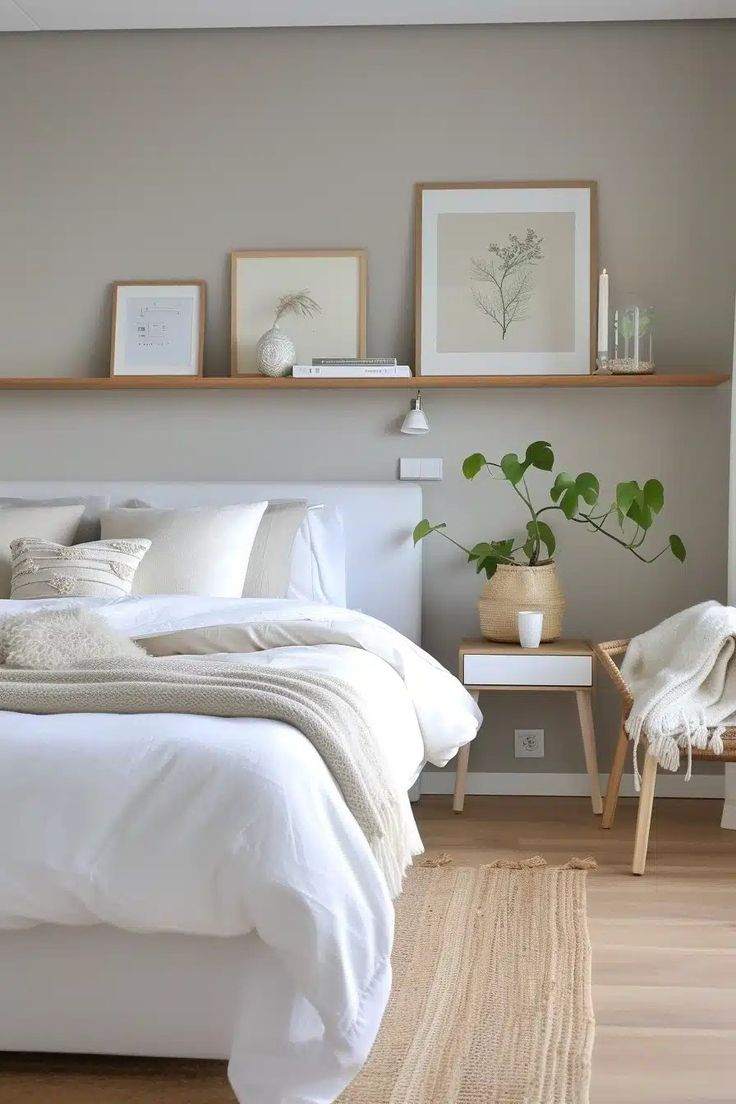 a white bed sitting in a bedroom next to a wooden shelf with pictures on it