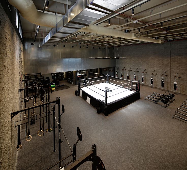 an empty boxing ring in a gym with benches and lights hanging from the ceiling above