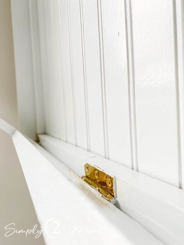 a close up of a door handle on the side of a white door with wood paneling