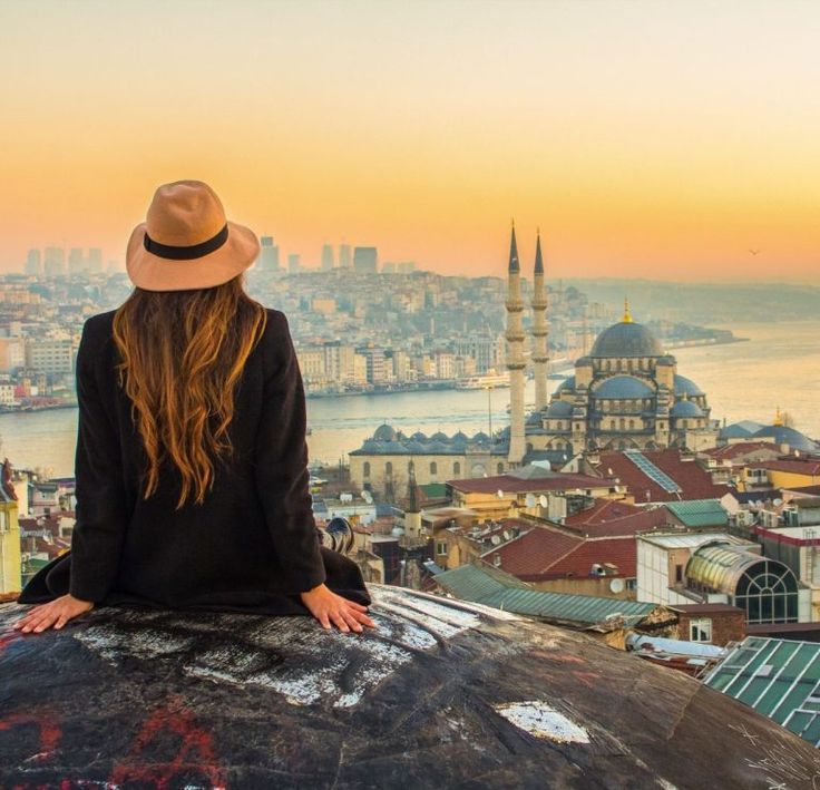 a woman sitting on top of a building looking at the city