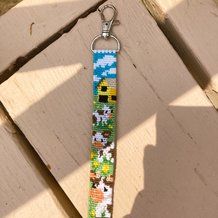 a keychain made out of beads and fabric with sheeps on the grass