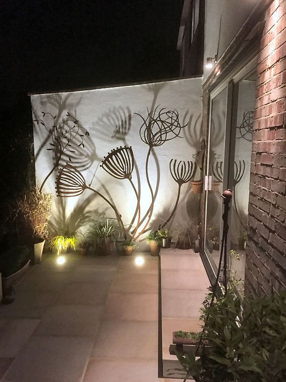 an outdoor area with plants and lights on the side of the building, at night