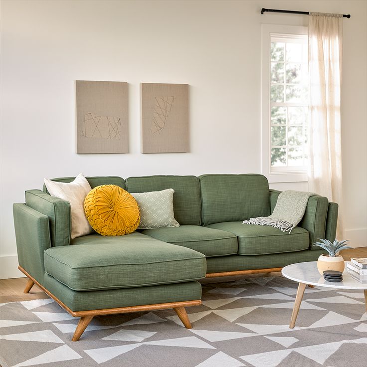 a living room with a green couch and two paintings on the wall