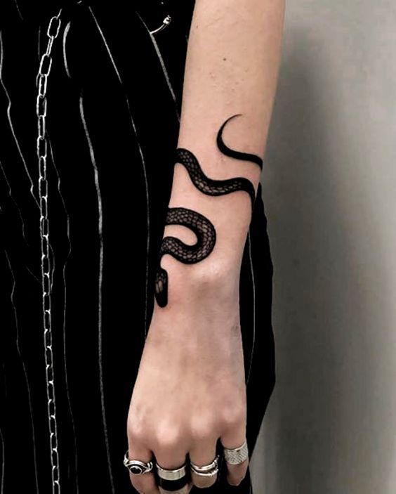 a woman with a snake tattoo on her left arm and two rings around her wrist