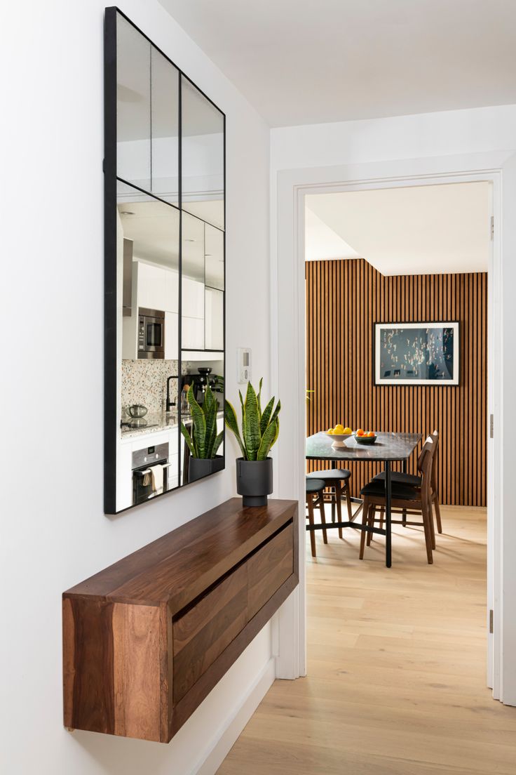 a dining room with a table, mirror and plant on the wall next to it