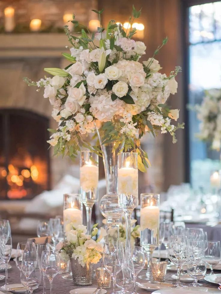 a table set with candles and flowers in tall vases