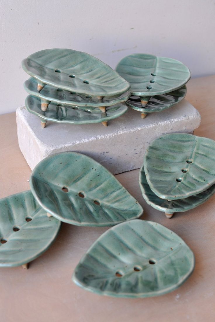 four green leaf shaped plates sitting on top of a counter next to a white box