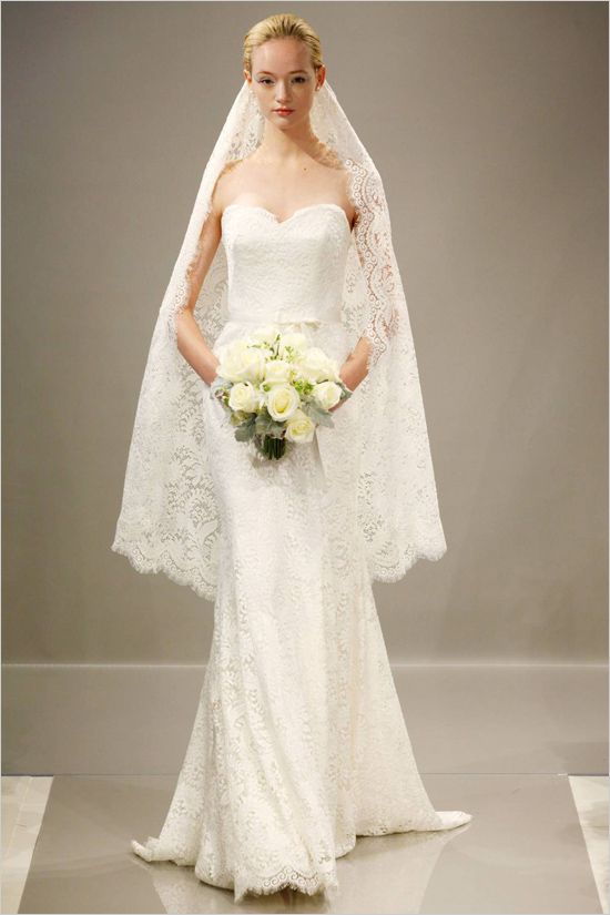 the bride is walking down the runway with her bouquet in hand and she is wearing a white wedding dress