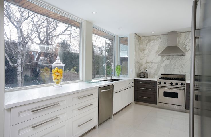 a kitchen with marble counter tops and stainless steel appliances, along with large windows that look out onto the backyard