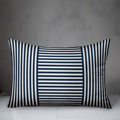 a black and white striped pillow sitting on top of a table in front of a gray wall