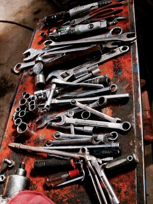 there are many wrenches and other tools on the table in front of someone's feet