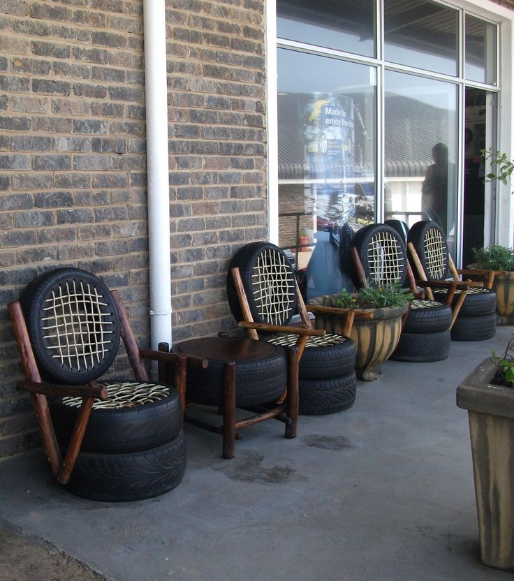 four chairs are lined up against a brick wall with planters on the sidewalk in front of them