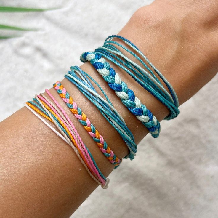 a woman's arm with several different colored bracelets on it