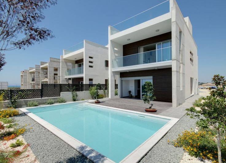 an empty swimming pool in front of a modern house