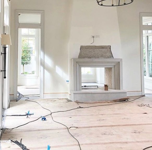 an empty room with a fireplace in the middle and wires on the floor around it