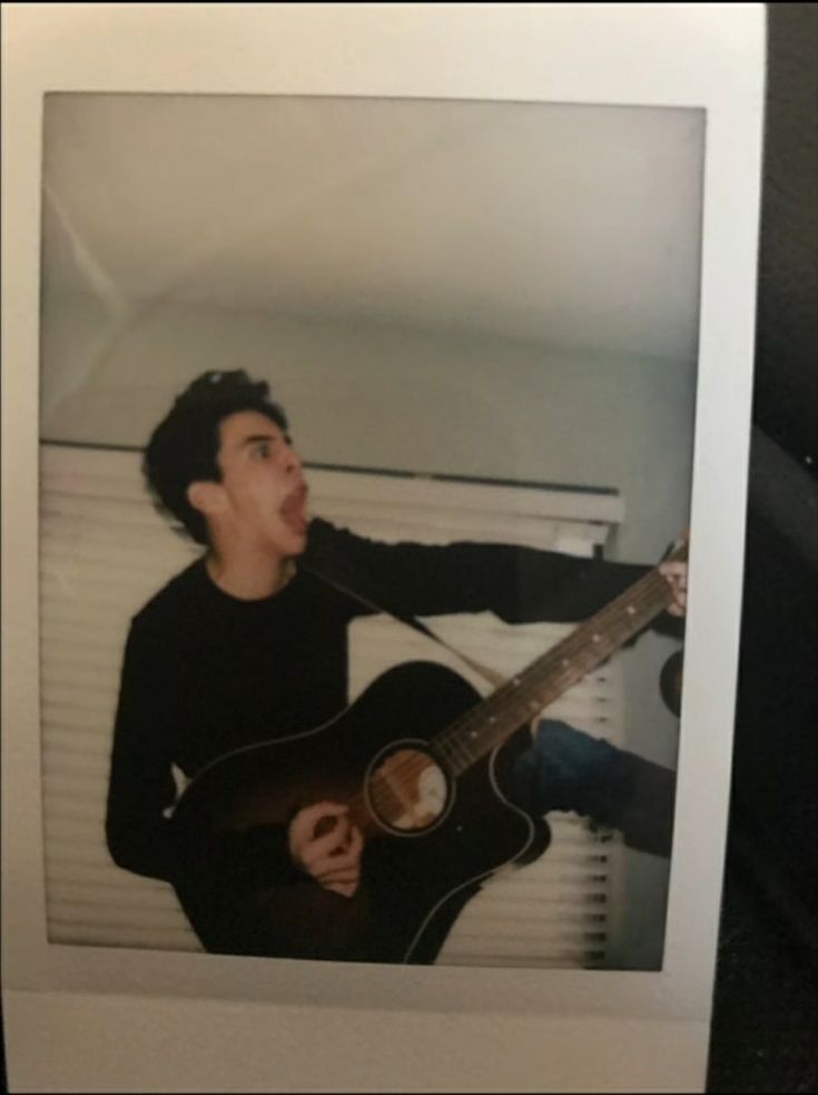 an old photo of a man holding a guitar