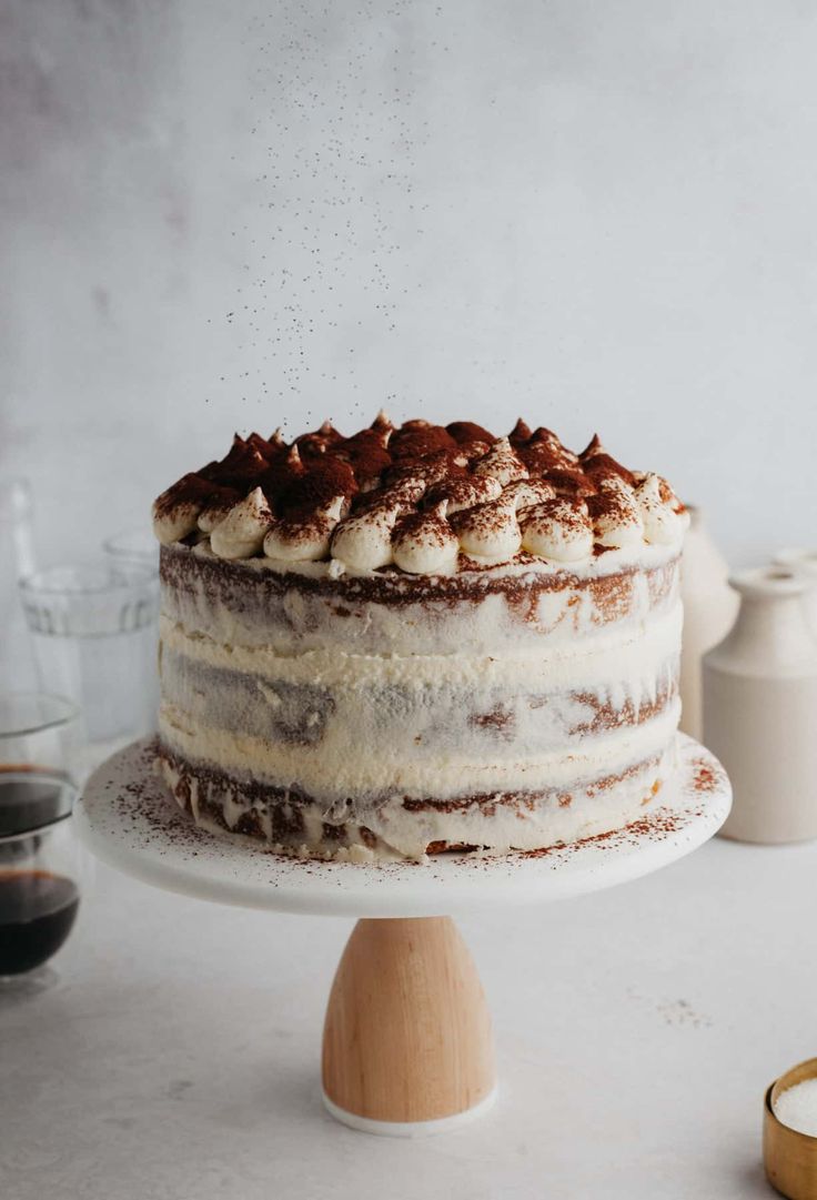 a cake with white frosting and chocolate sprinkles on top is sitting on a plate