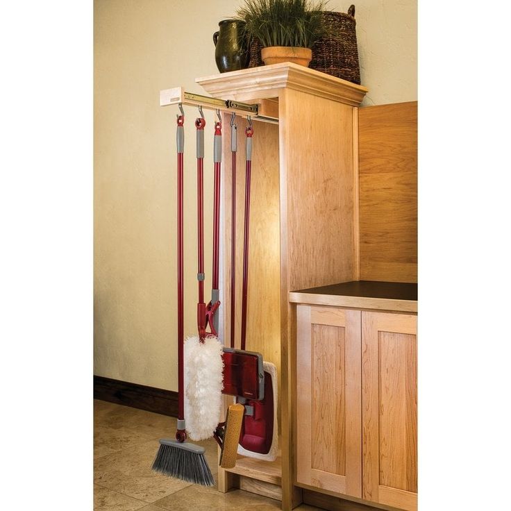 a coat rack with brooms and boots hanging from it's sides in a kitchen