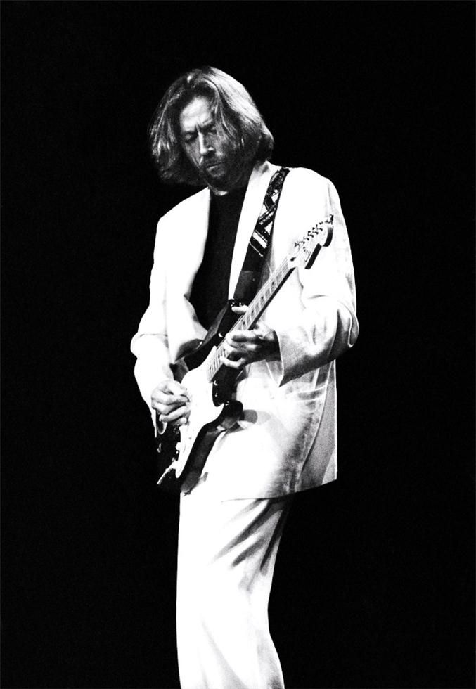 a man in white suit playing an electric guitar