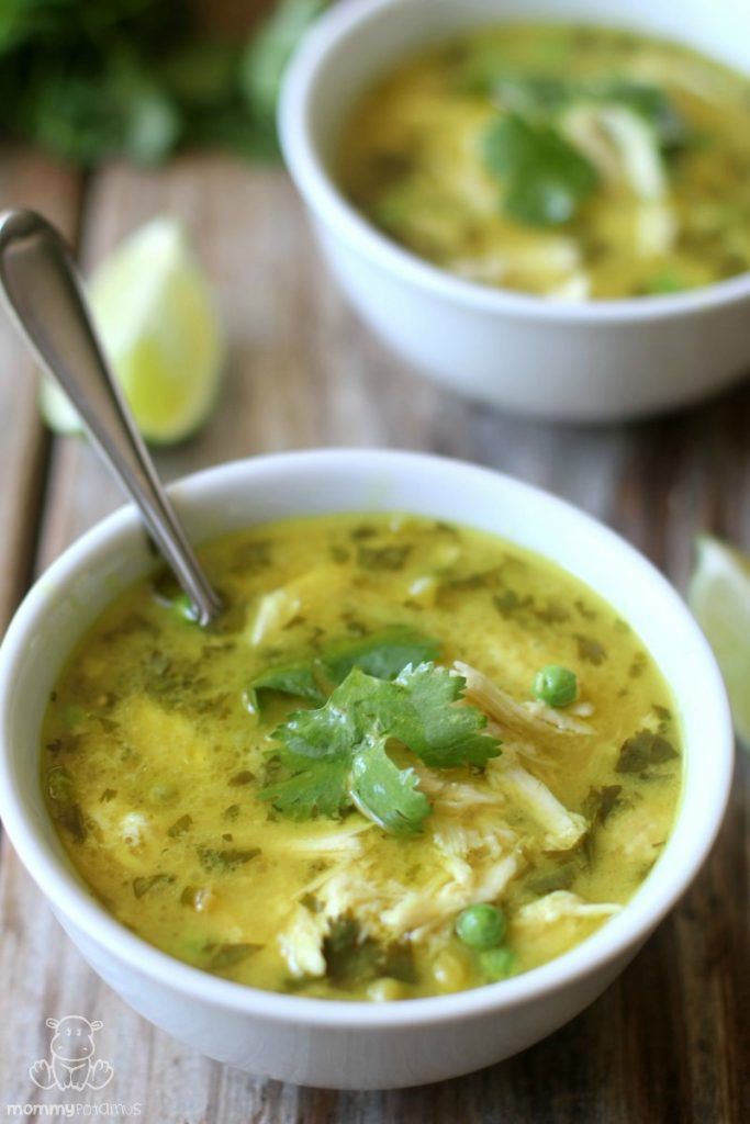 two white bowls filled with soup and garnished with cilantro, parsley and lime