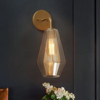 a light that is on the wall next to a vase with flowers and a potted plant