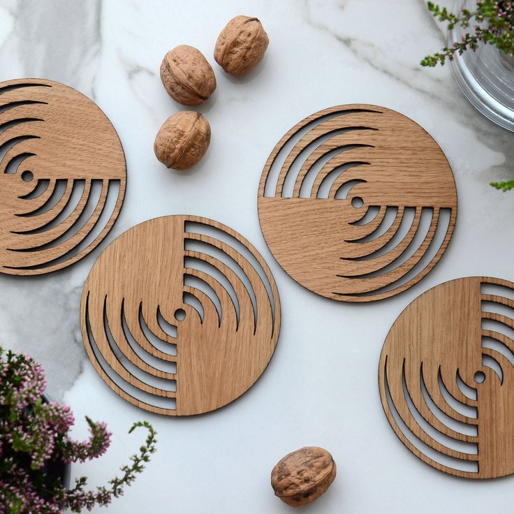 four wooden coasters sitting on top of a white table next to nuts and flowers